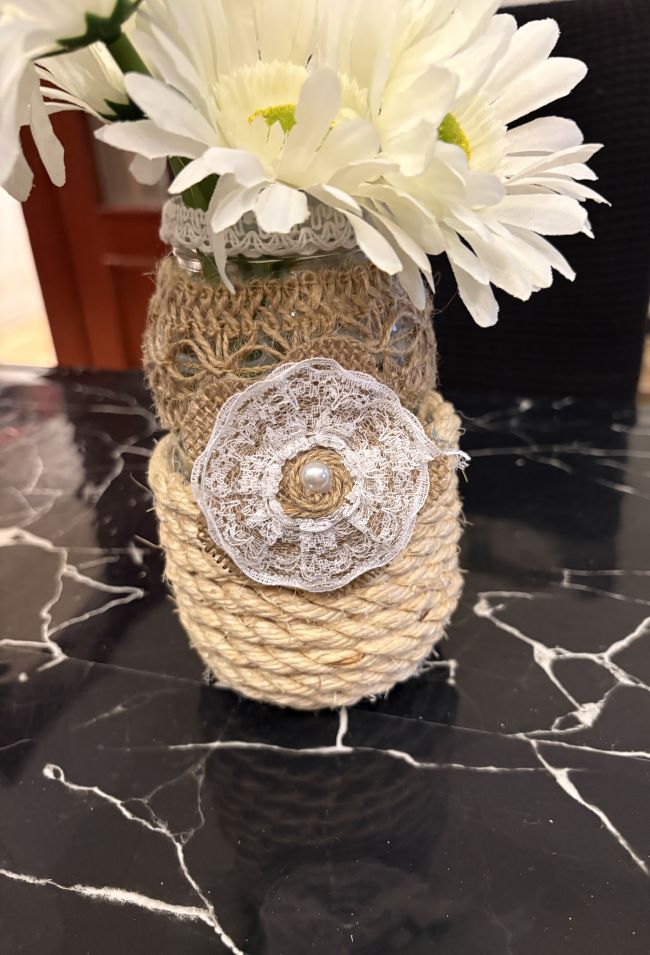 PEQUEÑO JARRON DE VIDRIO DECORADO CON YUTE Y FLORES ARTIFICIALES