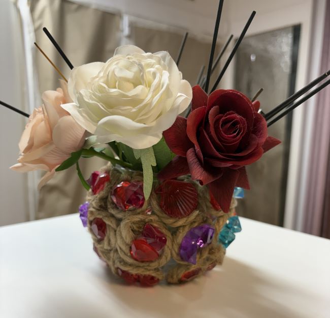 JARRON DE VIDRIO CON YUTE Y DECORADO CON PIEZAS DE COLORES Y FLOR ARTIFICIAL