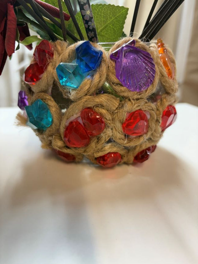 JARRON DE VIDRIO CON YUTE Y DECORADO CON PIEZAS DE COLORES Y FLOR ARTIFICIAL